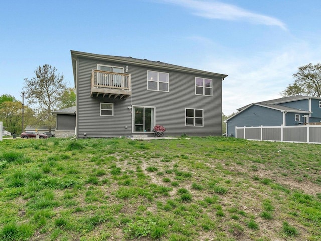 rear view of house featuring a balcony and fence