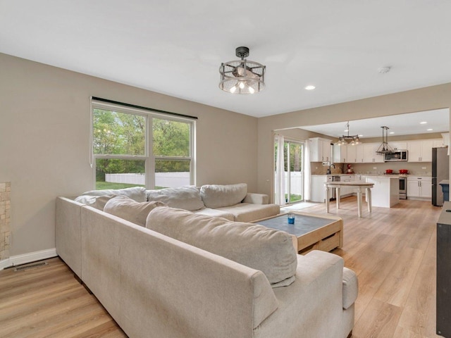 living room with light wood finished floors, visible vents, and recessed lighting