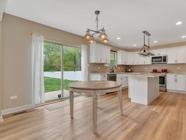 kitchen with stainless steel appliances, recessed lighting, light wood-style flooring, white cabinetry, and a center island