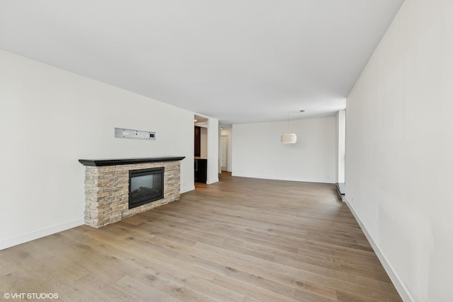 unfurnished living room featuring light wood-style floors, baseboards, and a fireplace