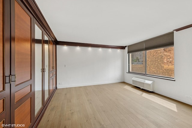 empty room featuring baseboards, ornamental molding, and light wood finished floors