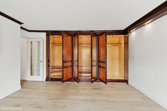 unfurnished bedroom featuring light wood-style floors, baseboards, and crown molding