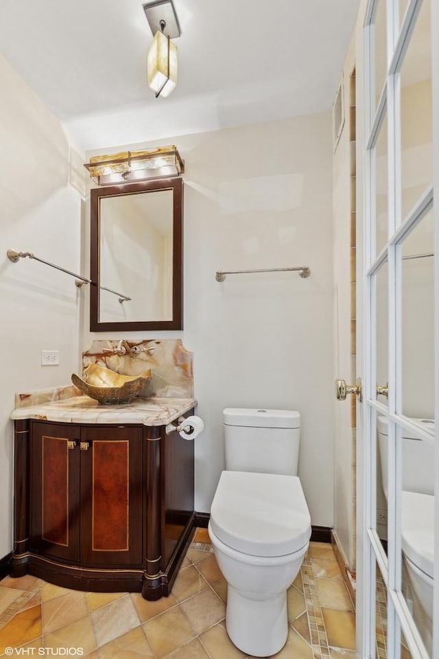 bathroom featuring vanity, baseboards, visible vents, and toilet