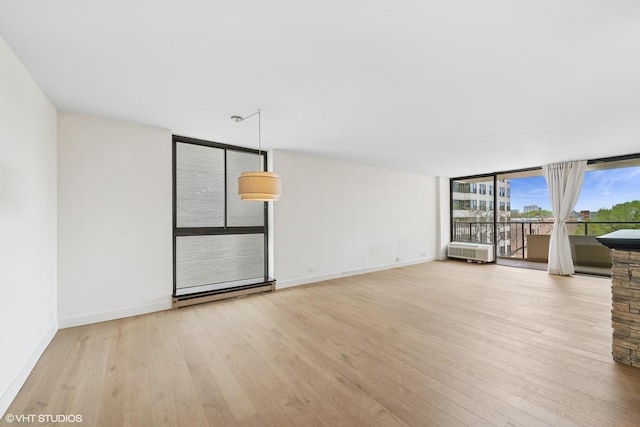 unfurnished living room featuring baseboards, a wall of windows, baseboard heating, and hardwood / wood-style floors