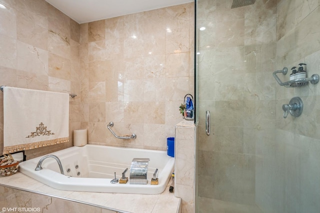 full bath with tile walls, a stall shower, and a tub with jets