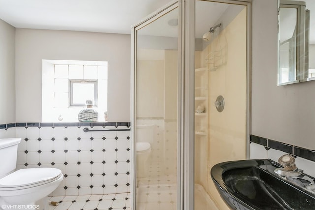 full bath featuring a sink, a stall shower, toilet, and tile walls