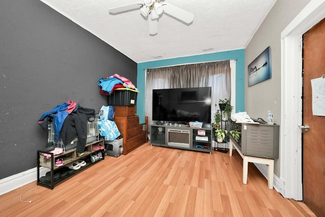 living area with a textured ceiling, a ceiling fan, and wood finished floors