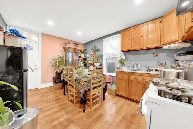 kitchen with light countertops, a sink, freestanding refrigerator, white range with gas cooktop, and light wood-style flooring