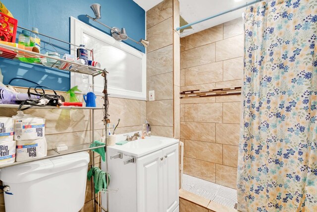 bathroom featuring vanity, a stall shower, toilet, and tile walls