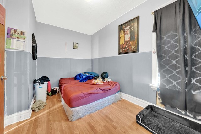 bedroom featuring wainscoting and wood finished floors