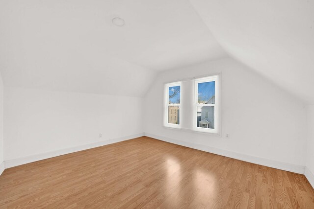 additional living space featuring baseboards, wood finished floors, and vaulted ceiling