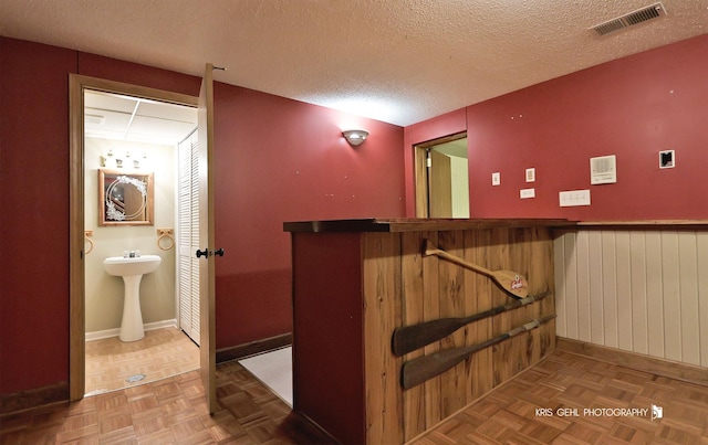 interior space featuring wood walls, a textured ceiling, and a sink