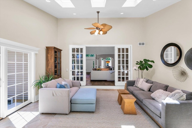 living room with a skylight, visible vents, and a towering ceiling
