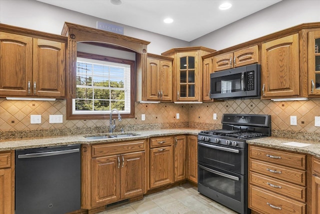 kitchen featuring double oven range, a sink, light stone counters, stainless steel microwave, and dishwashing machine