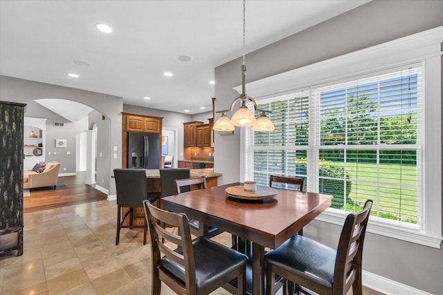 dining area featuring arched walkways, baseboards, recessed lighting, and light tile patterned floors