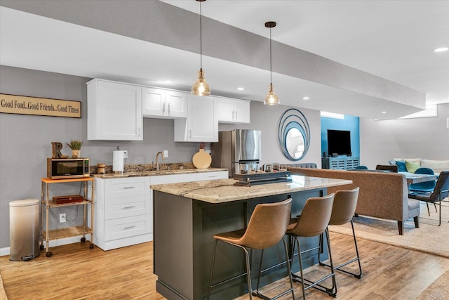 kitchen featuring light wood-style floors, appliances with stainless steel finishes, white cabinets, and light stone countertops
