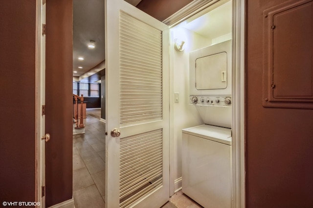 clothes washing area with laundry area, light tile patterned floors, and stacked washer / drying machine