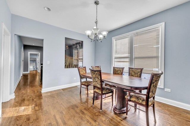 dining space featuring baseboards, wood finished floors, and a notable chandelier