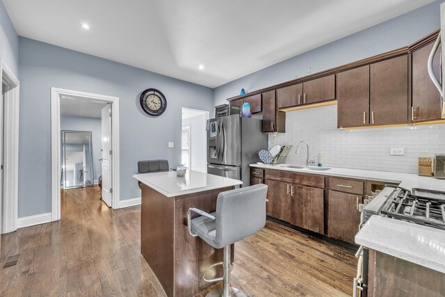 kitchen with decorative backsplash, a kitchen island, dark wood-style floors, stainless steel fridge with ice dispenser, and a sink