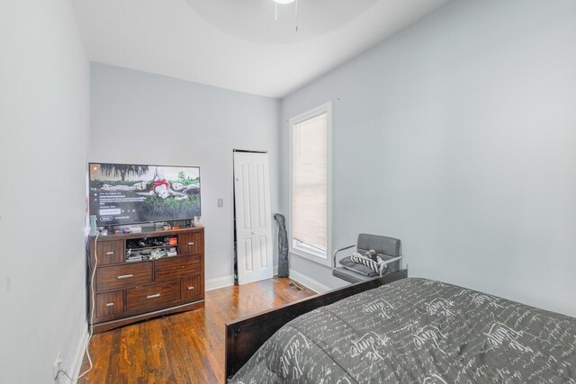 bedroom with baseboards, ceiling fan, wood finished floors, and a closet