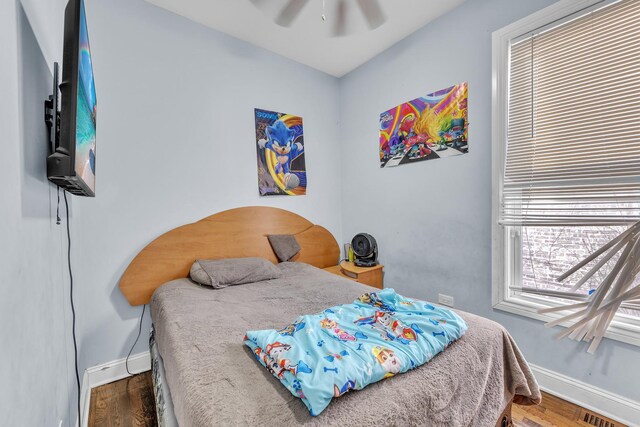 bedroom with a ceiling fan, baseboards, visible vents, and wood finished floors