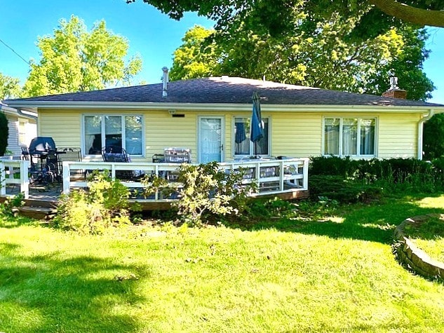rear view of house with a yard, a deck, and a chimney