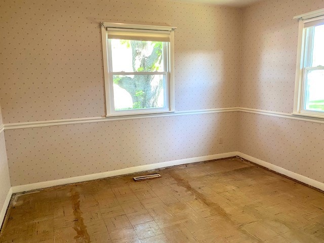 spare room with wallpapered walls, plenty of natural light, and visible vents
