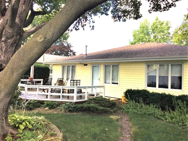 rear view of house featuring outdoor dining space, a wooden deck, and a shingled roof