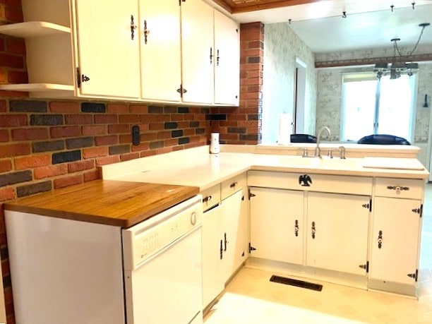 kitchen with a peninsula, a sink, open shelves, dishwasher, and decorative backsplash