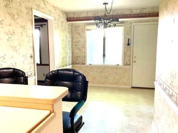 home office with a chandelier, baseboards, and wallpapered walls