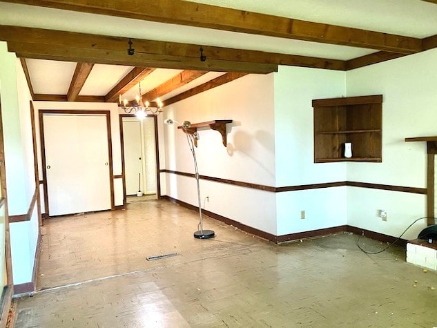interior space featuring a chandelier, baseboards, and beam ceiling