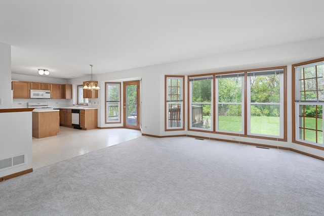 unfurnished living room featuring baseboards, light carpet, an inviting chandelier, and visible vents