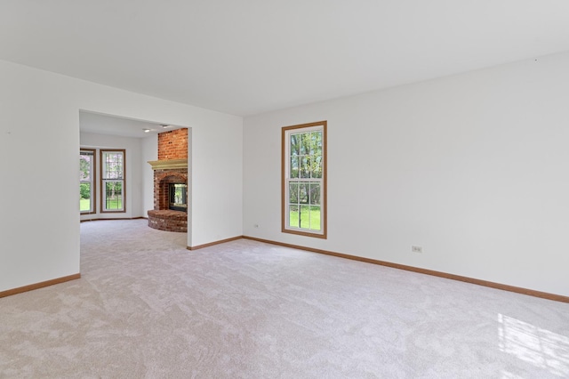 unfurnished living room featuring light carpet, baseboards, and a brick fireplace