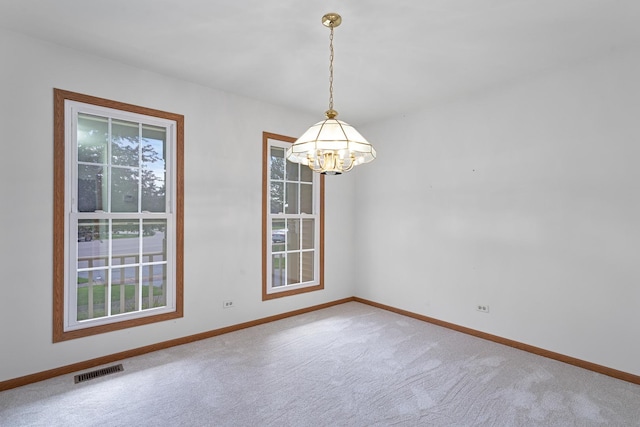 empty room with a chandelier, carpet, visible vents, and baseboards