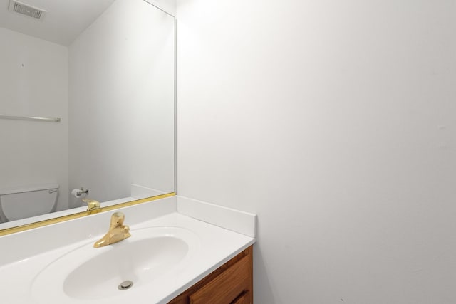 half bath featuring vanity, toilet, and visible vents