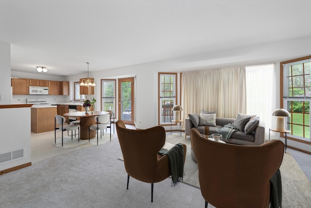living area featuring an inviting chandelier, light carpet, and a healthy amount of sunlight