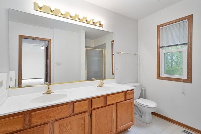 bathroom with a stall shower, toilet, a sink, and double vanity