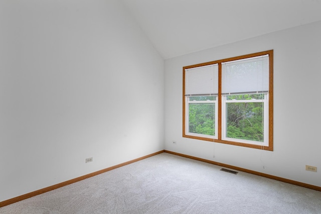 spare room featuring vaulted ceiling, carpet flooring, baseboards, and visible vents