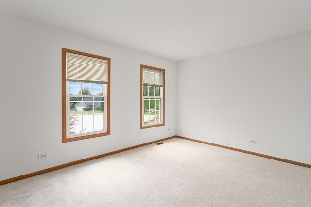 carpeted empty room featuring baseboards and visible vents