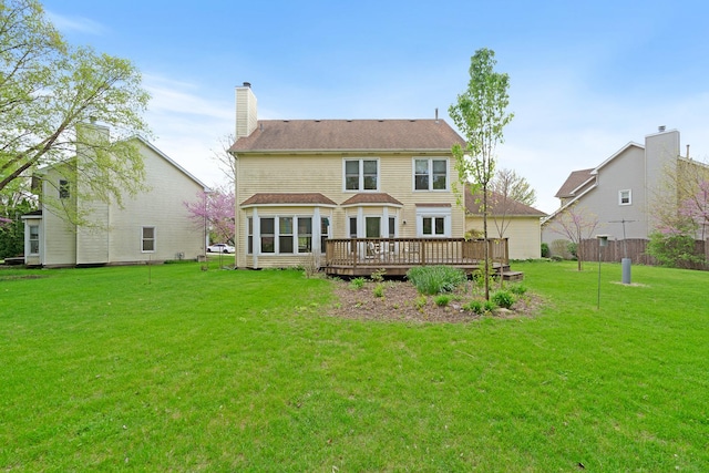 rear view of property with a wooden deck, a chimney, and a lawn