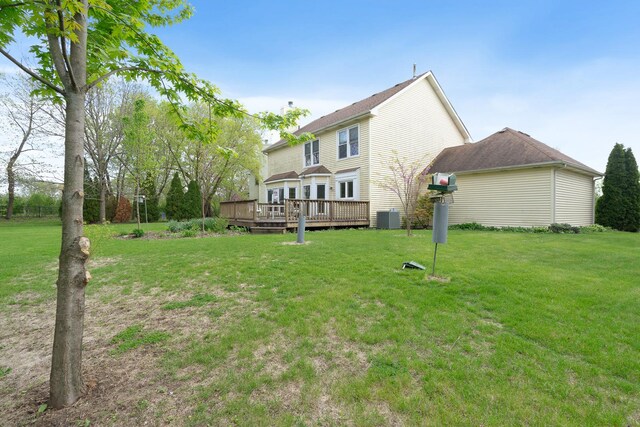 rear view of property featuring a yard, a deck, and cooling unit
