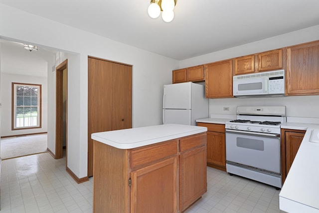kitchen with brown cabinets, white appliances, light countertops, and a center island