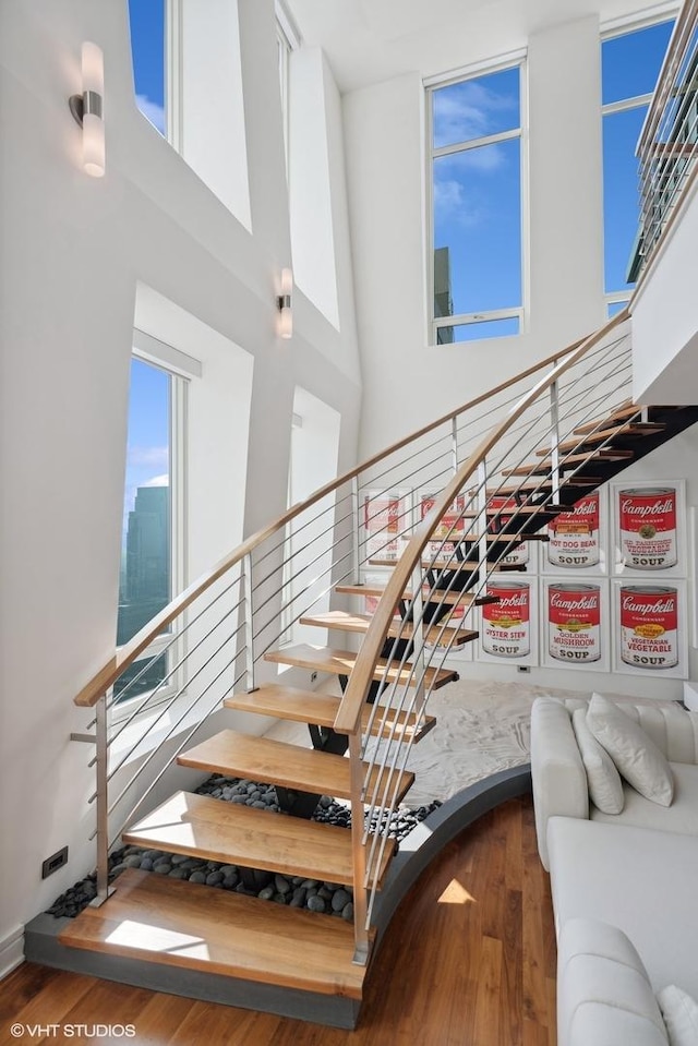 staircase featuring wood finished floors and a towering ceiling