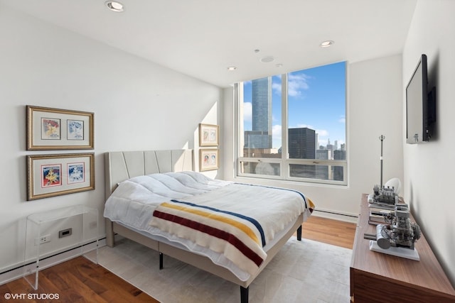 bedroom featuring recessed lighting, a baseboard heating unit, and wood finished floors