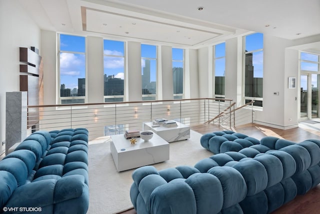living area with a view of city, recessed lighting, a tray ceiling, and wood finished floors