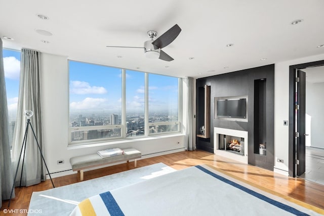 bedroom with a ceiling fan, a lit fireplace, recessed lighting, and wood finished floors