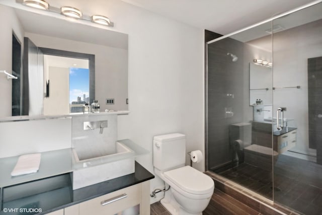 bathroom with vanity, wood finished floors, toilet, and a shower stall