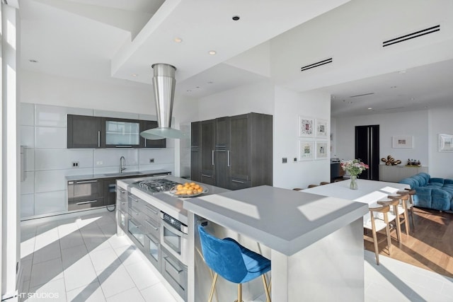 kitchen with visible vents, a kitchen island, open floor plan, a sink, and light tile patterned floors