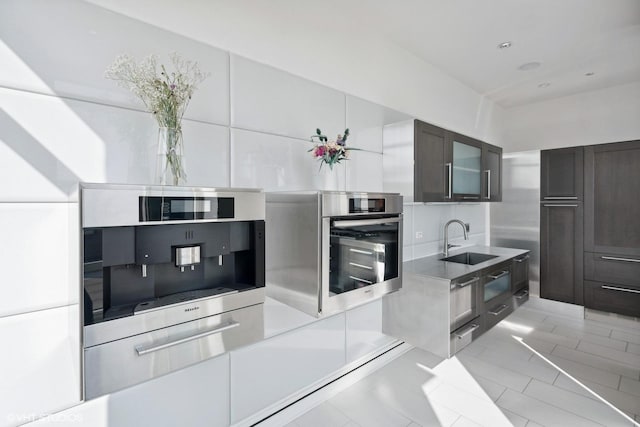 kitchen featuring light countertops, a sink, glass insert cabinets, and oven