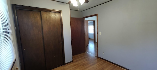 unfurnished bedroom with a closet, light wood-style flooring, baseboards, and ceiling fan